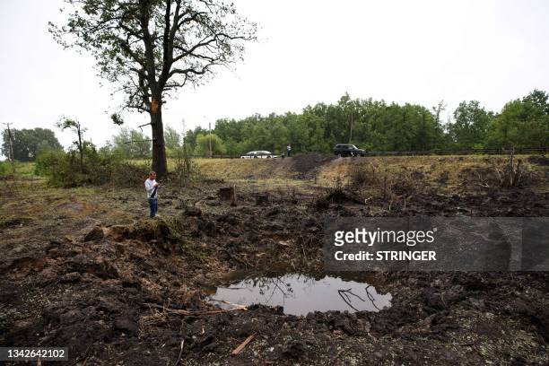 Man uses his smartphone to take pictures of a bomb crater on the side of a road outside the settlement of Anna in the Voronezh region on June 27,...