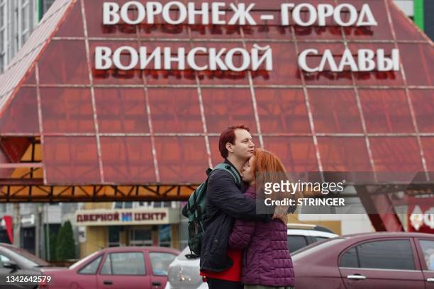 Couple embraces in front of a street decoration reading "Voronezh - is the City of Military Glory" in Voronezh on June 27, 2023. Bomb craters,...