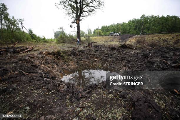 Man walks next to a bomb crater on the side of a road outside the settlement of Anna in the Voronezh region on June 27, 2023. Bomb craters, shelled...