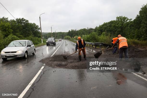 Workers repair a road damaged during the Wagner mercenaries rebellion outside the settlement of Anna in the Voronezh region on June 27, 2023. Bomb...