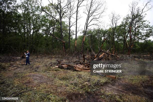 Man takes pictures with his smartphone next to trees damaged during the Wagner mercenaries rebellion on the side of a road outside the settlement of...