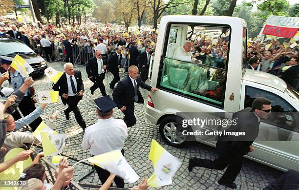 Bodyguards rush as the popemobile drives between crowds on the way the Kalwaria Zebrzydowska sanctuary August 19, 2002 in Krakow, Poland. Pope John...