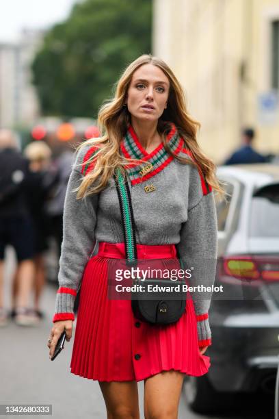 Guest wears a pale gray wool with red and green stripes pullover from Philosophy with gold brooch, a black shiny leather crossbody bag from...