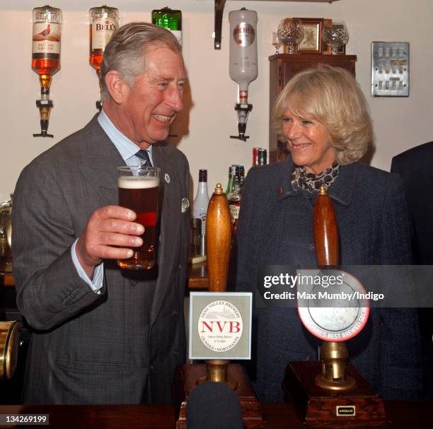 Prince Charles, Prince of Wales pulls a pint of 'Newton's Drop' beer as Camilla, Duchess of Cornwall looks on whilst they visit the Cholmeley Arms...