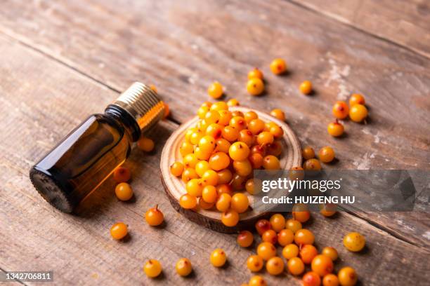 sea buckthorn essential oil with sea buckthorn berries - buckthorn stock pictures, royalty-free photos & images