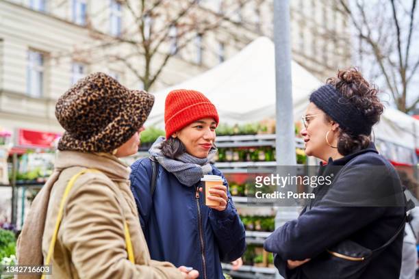 gruppe von freundinnen, die auf dem lokalen markt stehen und sich unterhalten - discussion germany outdoor friends stock-fotos und bilder