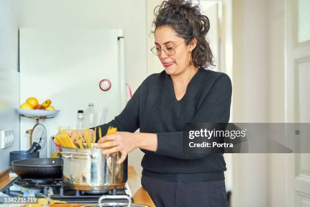 frau, die spaghetti pasta zu hause zubereitet - one pot pasta stock-fotos und bilder