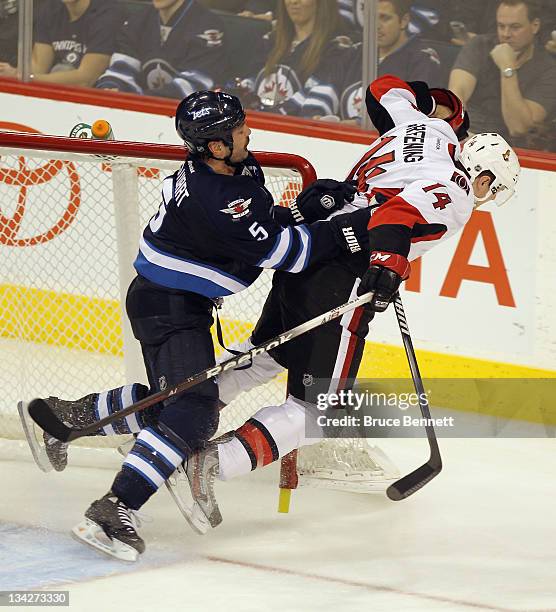 Mark Stuart of the Winnipeg Jets runs Colin Greening of the Ottawa Senators out of the crease in the third period at the MTS Centre on November 29,...