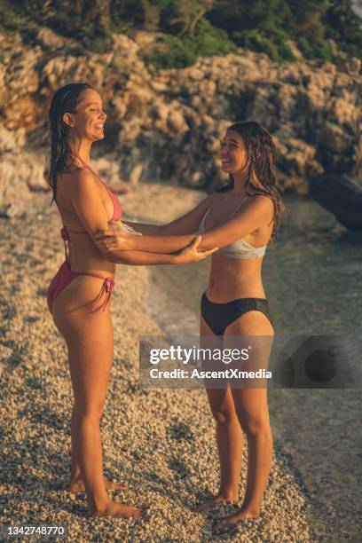 junge frauen entspannen sich bei sonnenaufgang am felsigen strand - croatia girls stock-fotos und bilder