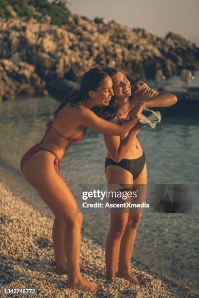 las mujeres jóvenes se relajan en la playa rocosa al amanecer - croatia girls fotografías e imágenes de stock