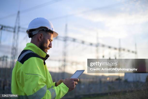 electictical engineer usung digital tablet in power station - hard hat stock pictures, royalty-free photos & images