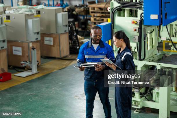 industrial and manufacturing engineering, quality control and management in a production process. african supervisor explaining to asian junior engineer by engineering parts. they are discussing in front of mechanical press machine over component parts. - conversation car bildbanksfoton och bilder