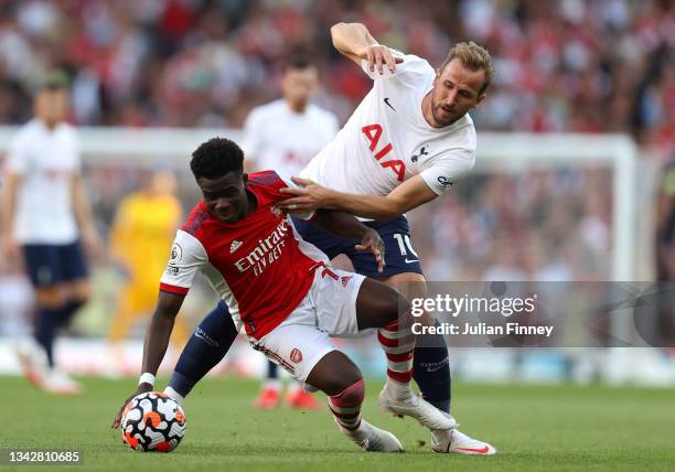 Bukayo Saka of Arsenal is challenged by Harry Kane of Tottenham Hotspur during the Premier League match between Arsenal and Tottenham Hotspur at...