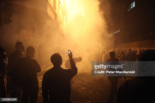 Youth films the aftermath of a tear gas volley fired by police on protestors in Muhammed Mahmoud Street near Tahrir Square on November 23, 2011 in...