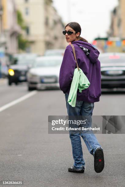 Model wears sunglasses, a dark purple hoodie sweater white black and white print pattern yoke from Supreme, a shoulder bag, a pale green t-shirt,...