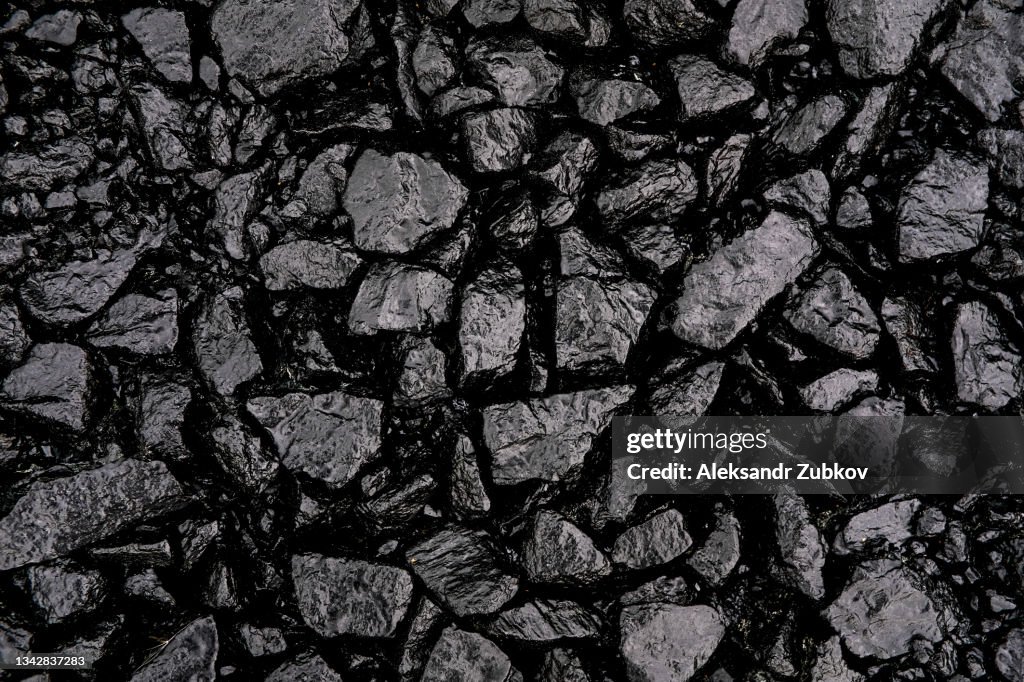 Gray or black gravel or crushed stone for road construction and reconstruction, poured with bitumen. Preparation and Laying of asphalt. Textured background. Construction industry.