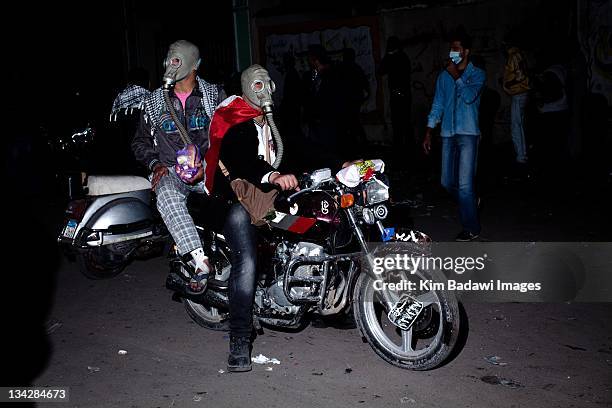 Men on motocycles carry injured from the frontlines to medical stations after street battles with Egyptian security forces on in smaller alleyways...