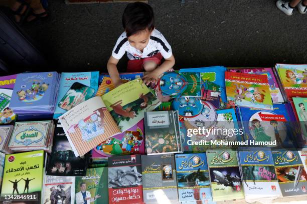 Yemeni child reads children's story book while visiting the book fair opened as an opportunity to enable people to buy books with reduced prices...