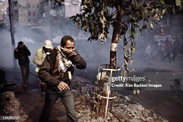 Demonstrators run from tear gas during battles with Egyptian security forces on in smaller alleyways off Mohamed Mahmoud in downtown Cairo on...