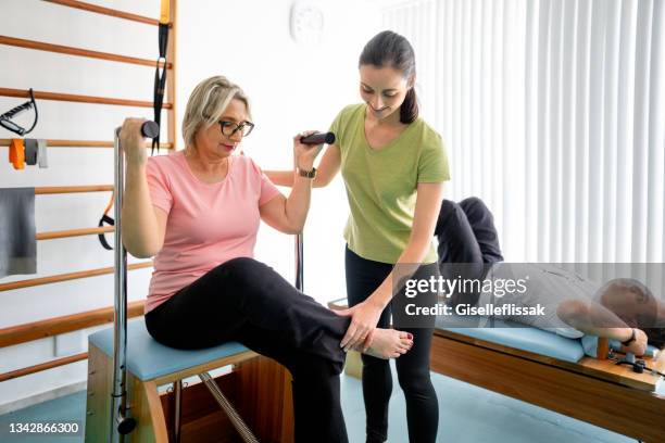 smiling young pilates instructor working with a female patient - pilates stock pictures, royalty-free photos & images