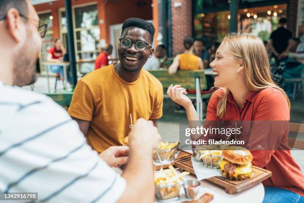 amici e fast food - adults eating hamburgers foto e immagini stock