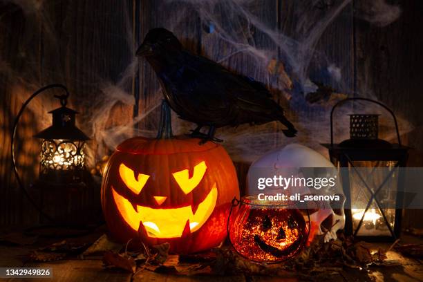 halloween jack-o-lantern pumpkins on rustic wooden background - raven skull stock pictures, royalty-free photos & images