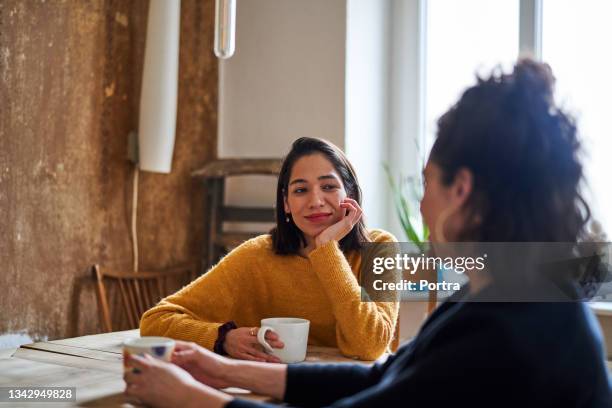 female friends talking over coffee at home - female with friend in coffee stock pictures, royalty-free photos & images