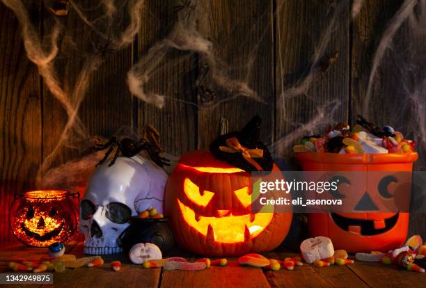 halloween pumpkins with pile of candies on rustic wooden background - raven skull stock pictures, royalty-free photos & images