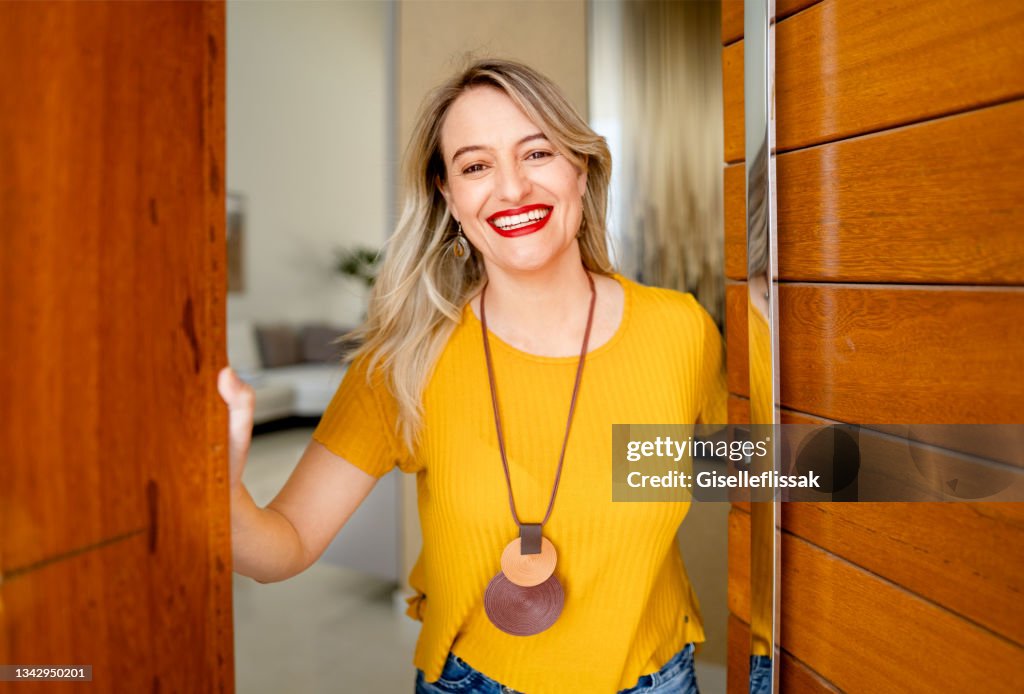Smiling woman standing at the open front door of her home