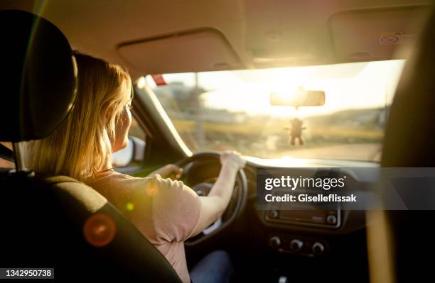 woman driving her car on a road on a late summer afternoon - person driving a car stock pictures, royalty-free photos & images