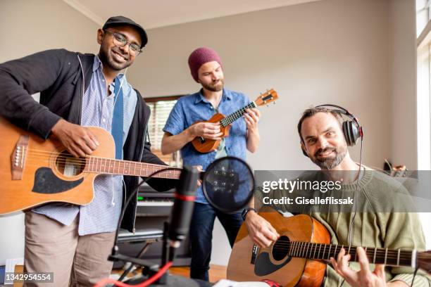 smiling band playing an acoustic music session in a home studio - acoustic music stockfoto's en -beelden