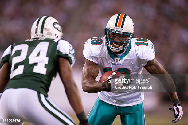 Miami Dolphins wide receiver Brandon Marshall runs the ball as the New York Jets cornerback Darrelle Revis defends during the game at MetLife Stadium...