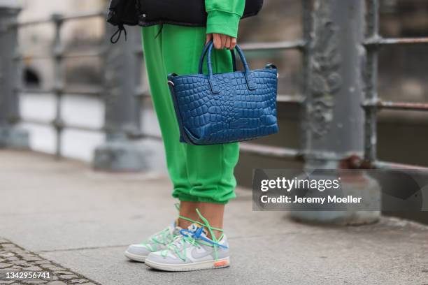 Sonia Lyson wearing colorful Off White x Nike sneakers, green Zara sweat set, black Prada vest, blue Liebeskind bag and Vera Wang shades on September...