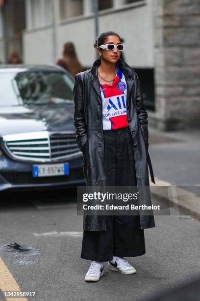 Guest wears white sunglasses, silver earrings, a silver chain necklace, a silver large chain necklace, a white with blue and red print pattern...