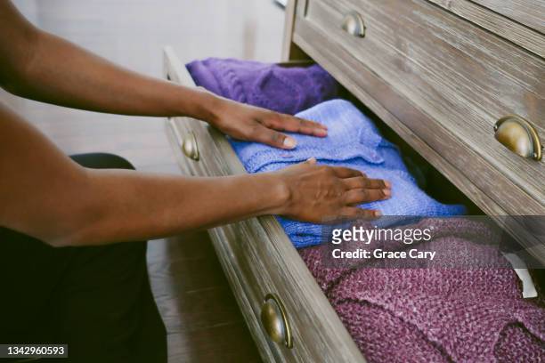 woman organizes sweaters in drawer - chest of drawers stock pictures, royalty-free photos & images