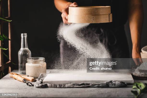 woman sifting flour through old sieve on kitchen board - sifting stock pictures, royalty-free photos & images