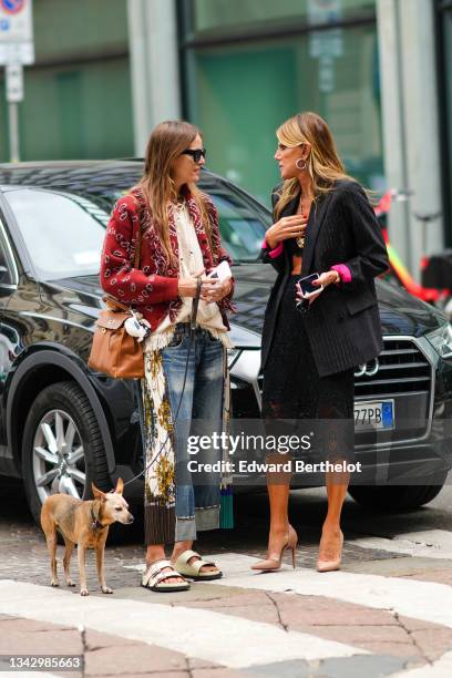 Guest wears sunglasses, necklaces, a white fringed t-shirt, a red with black and white print pattern wool jacket, a camel shiny leather shoulder bag,...