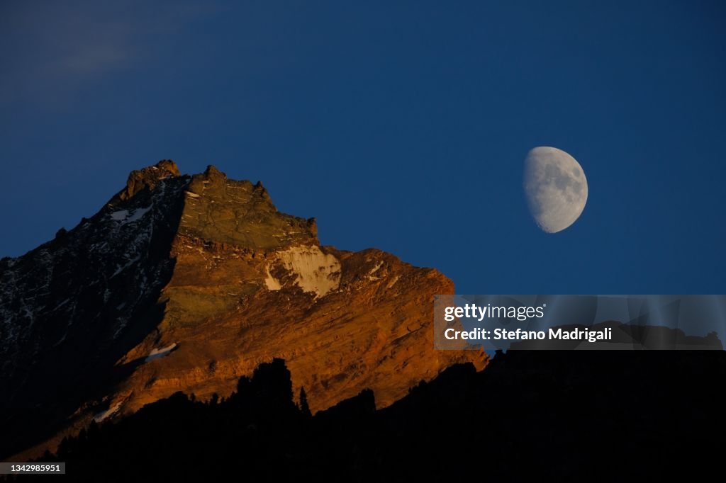 Natural alpine landscape grivola peak with moon in the middle of the evening blue hour