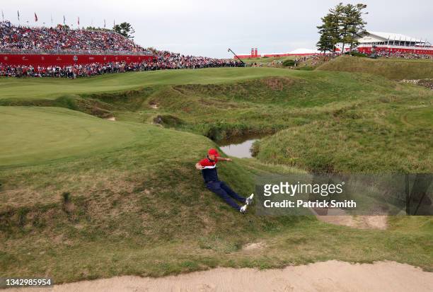 Bryson DeChambeau of team United States slides down an incline on the 18th hole as he celebrates their win over Team Europe during Sunday Singles...