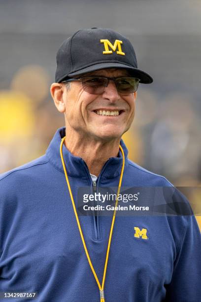 Jim Harbaugh warms up with players before the game against the Rutgers Scarlet Knights at Michigan Stadium on September 25, 2021 in Ann Arbor,...