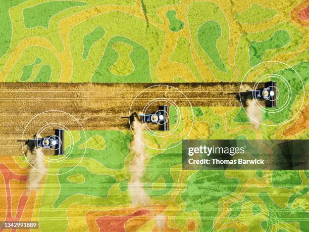 extreme wide shot overhead aerial view of combines harvesting wheat on summer afternoon with yield map overlay - farm machinery stock-fotos und bilder