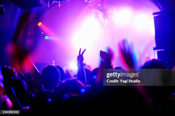 crowd with arms in air at nightclub music. - concierto fotografías e imágenes de stock