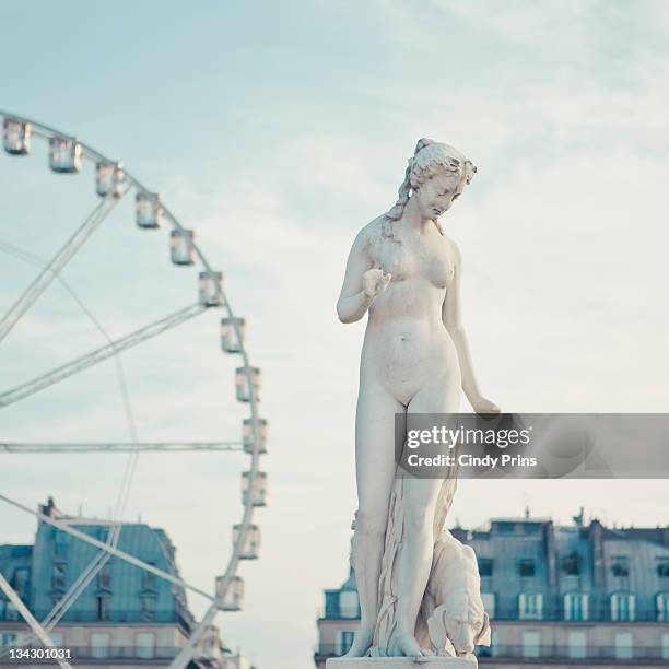 statue of naked lady and carrousel in back - statue paris photos et images de collection