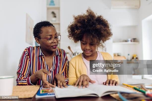 senior woman helping her granddaughter with homework - home school stock pictures, royalty-free photos & images