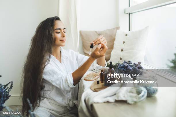 woman with long hair using serum for hair loss treatment. - skin care ingredients stock pictures, royalty-free photos & images