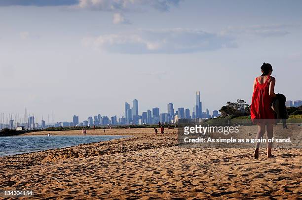 woman wearing red dress wallking on beach - brighton beach melbourne stock pictures, royalty-free photos & images