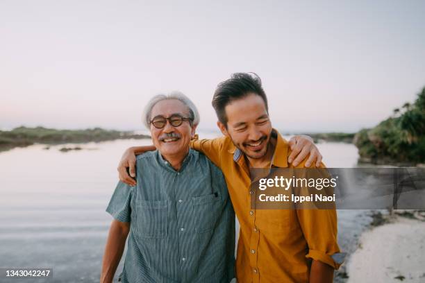 senior father and adult son having fun on beach at sunset, japan - asian smiling father son stock pictures, royalty-free photos & images