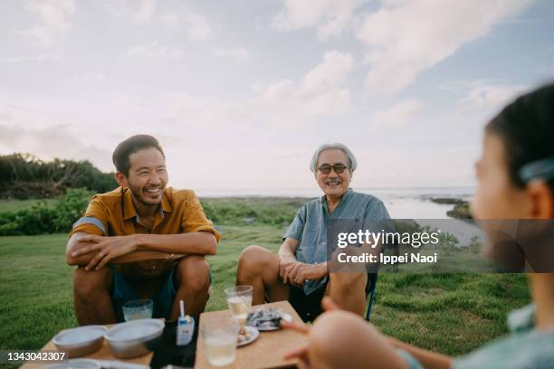 senior father and adult son having a good time on beach, japan - okinawa japan stockfoto's en -beelden