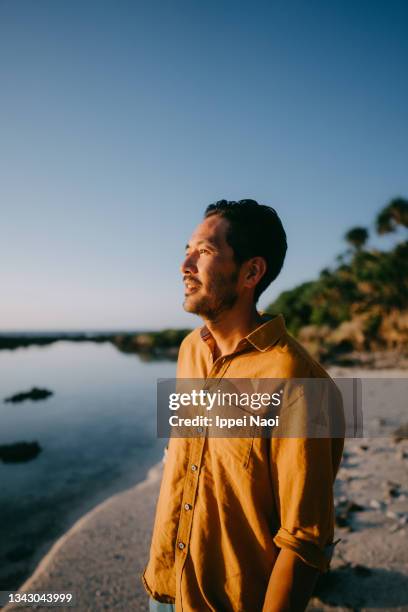 man on beach at sunset, japan - candid beach stock-fotos und bilder