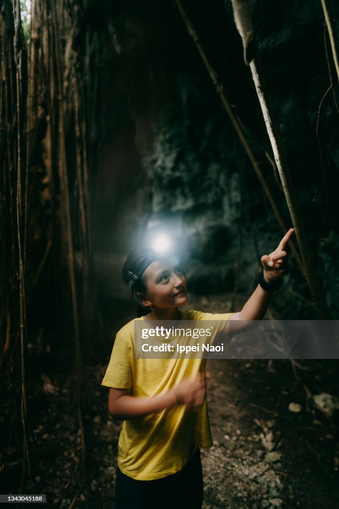 Young girl exploring cave with headlamp, Kikaijima, Japan